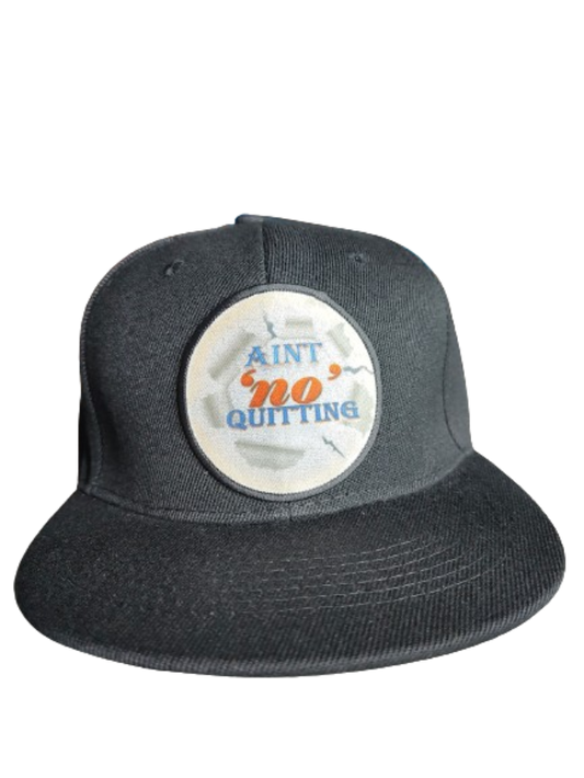  A black flat-brim baseball cap featuring a circular white patch on the front. The patch has a ripped paper effect around the edges and displays the motivational phrase "AIN'T 'NO' QUITTING" in blue and orange text. This cap is part of a never quit gift bundle, ideal for a fitness motivation gift set or empowerment apparel.
www.justsaynpromos.com